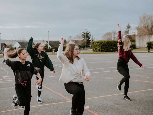 A group of young friends practices a dance routine. 
