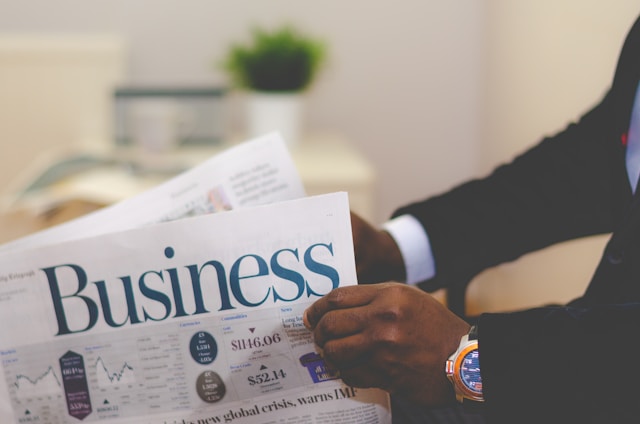 A man in a suit reads the business section of a newspaper. 
