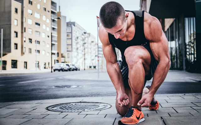 A runner stops to tie his shoelaces. 
