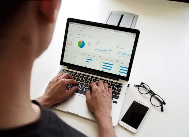 An analyst studies various graphs on his laptop. 
