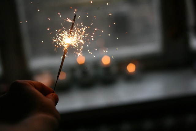 A person holds a small sparkler. 
