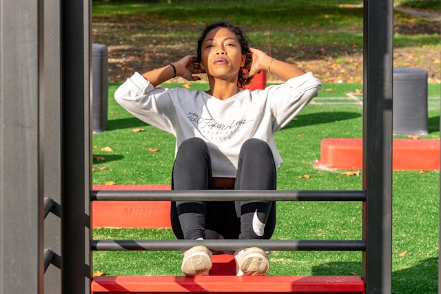 A woman does situps using equipment at the park. 
