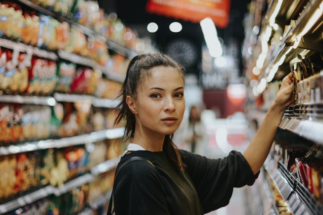 A shopper checks out the products on a grocery shelf. 
