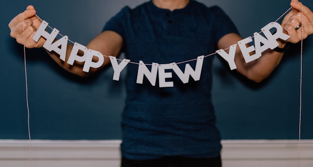 A person holds a “Happy New Year” string decoration. 
