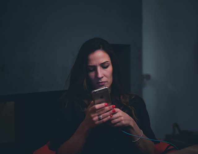 A woman browses TikTok videos on her phone. 
