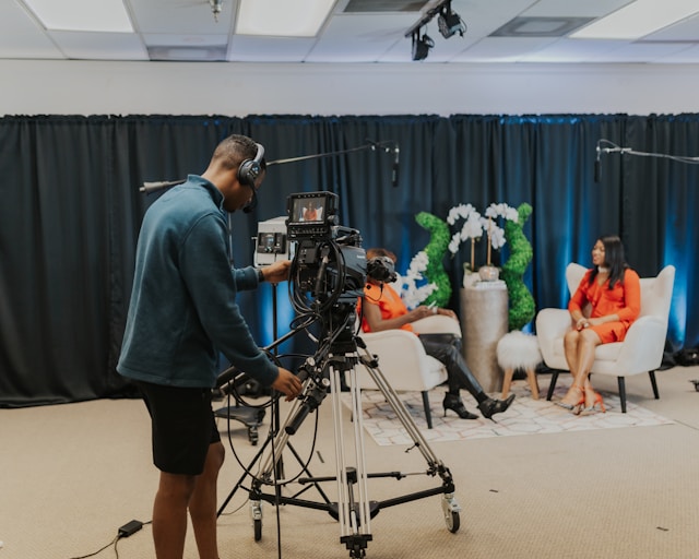 A man controls a DSLR camera to capture the livestream of two content creators.