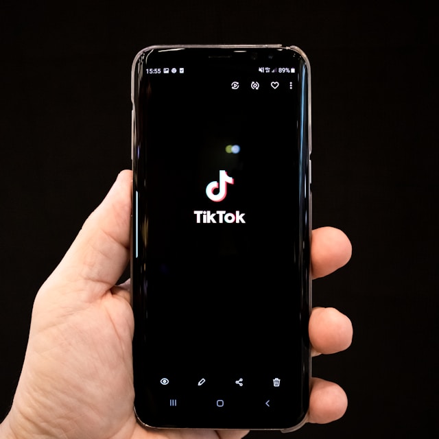 Someone holding a smartphone with the TikTok logo on its screen.
