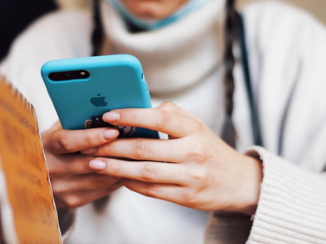 Someone uses a phone in a blue phone case.
