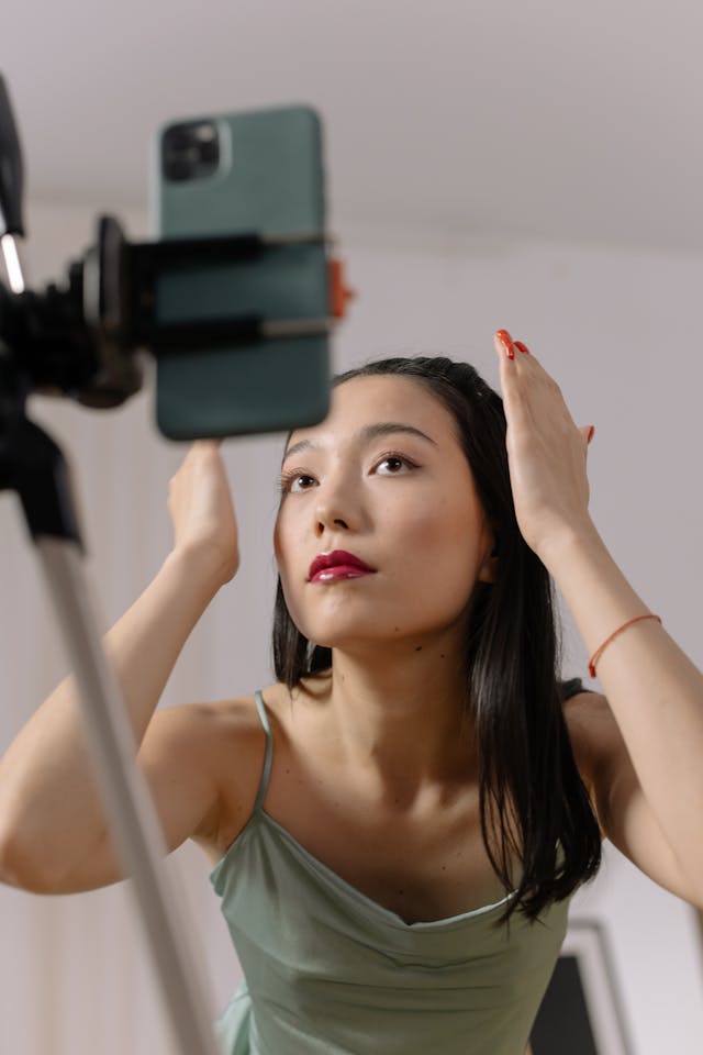 A woman fixes her hair in front of her camera.
