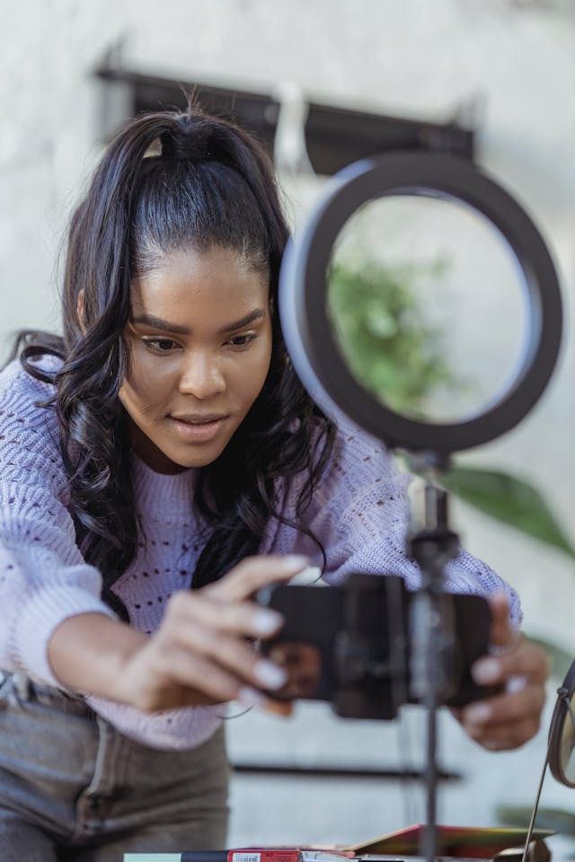 A woman leans in to adjust her phone screen.
