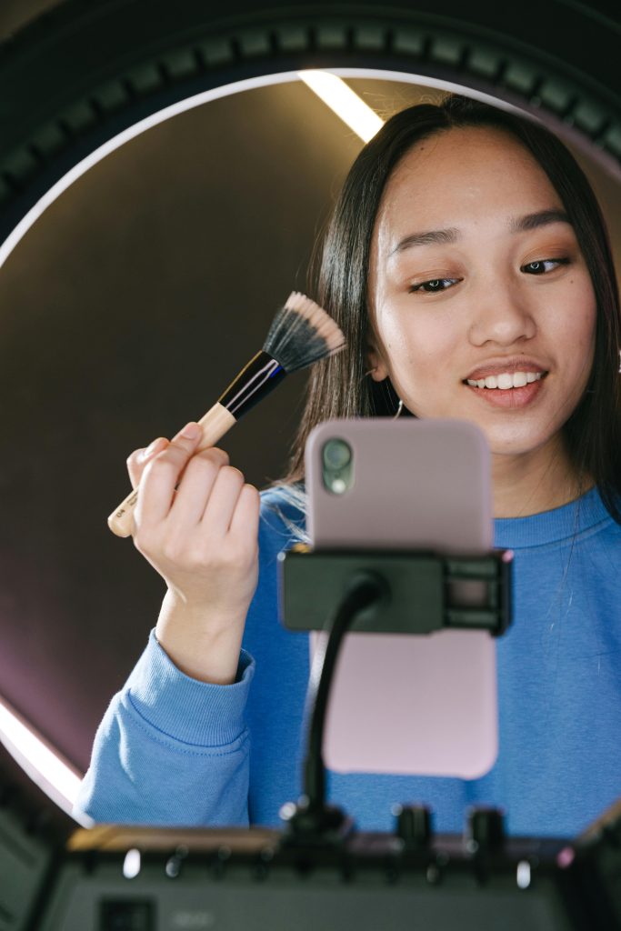 A woman records herself applying makeup.
