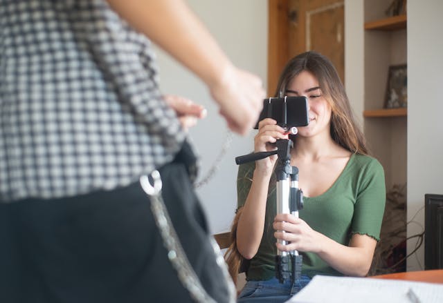 A woman records a man with her cell phone.
