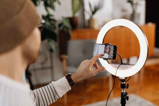 A man taps a phone screen mounted in front of a ring light.
