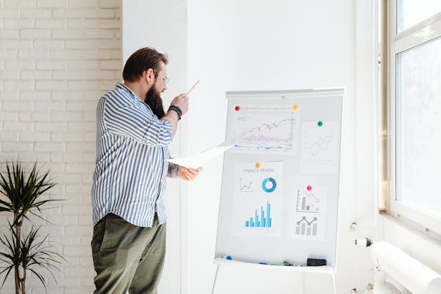 A man makes a presentation using several graphs.
