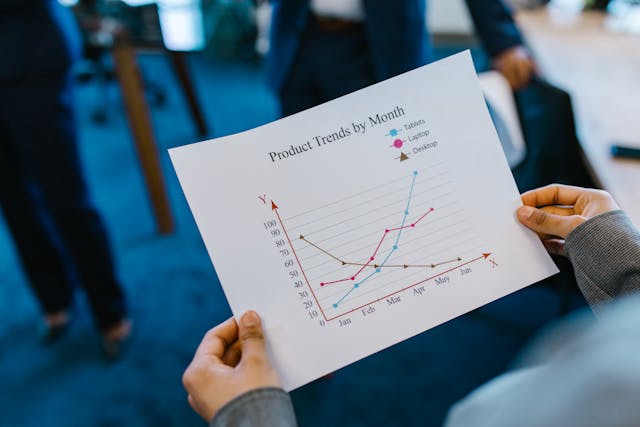 A person holds a sheet of paper showing product trends by the month.
