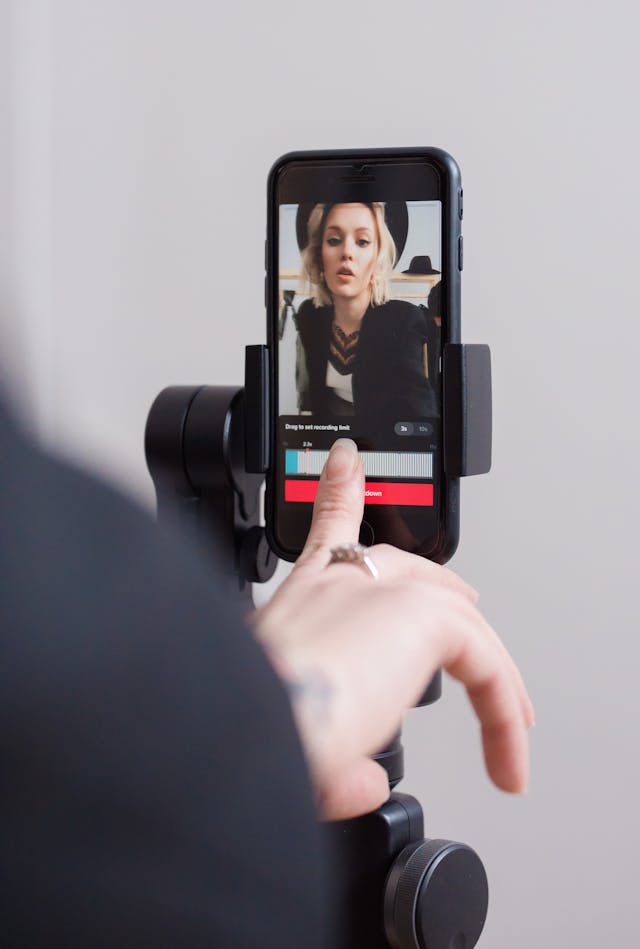 A woman taps on a phone screen while she records a video.
