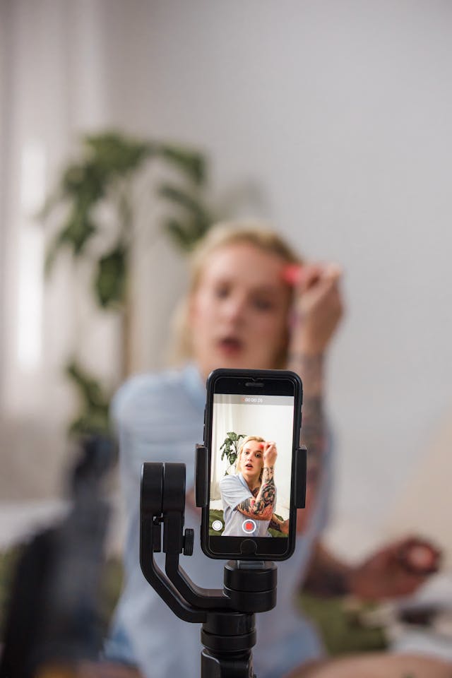 A camera records a woman putting on makeup.
