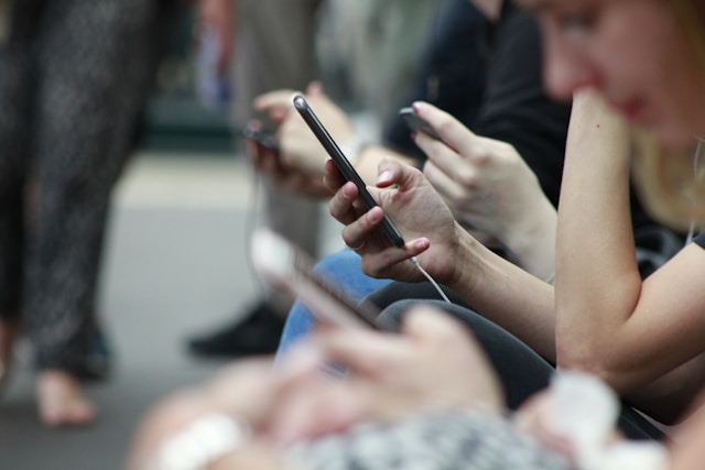 Commuters on a train watch videos on their phones. 
