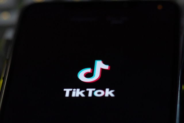 A phone screen displays the TikTok name and logo as the app loads. 

