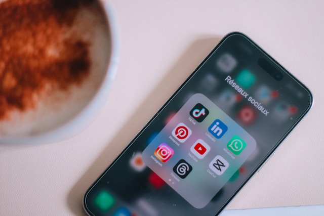 A mobile phone on a table shows a social media apps folder.
