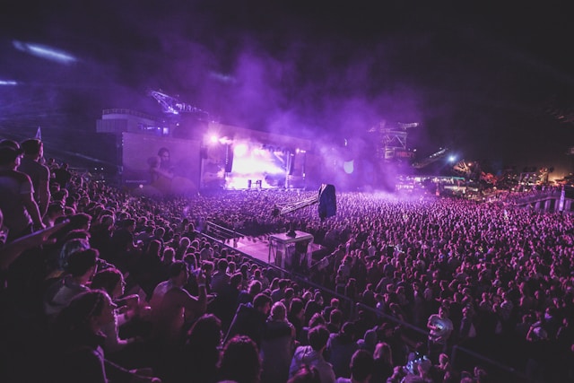 A big audience fills a stadium to watch a live concert. 
