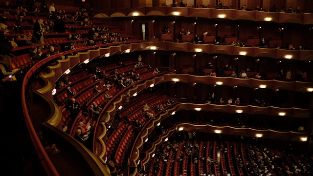 A theater slowly fills up with viewers. 
