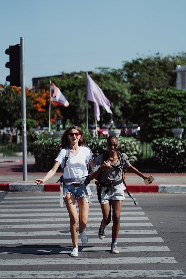 Two female friends running to cross the road together.