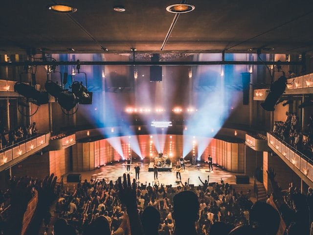 A big audience watches a live music performance on a stage. 
