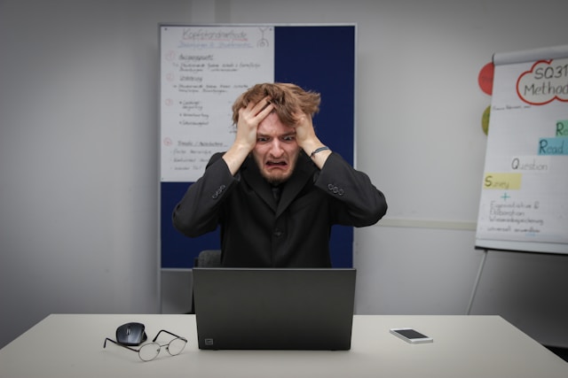 A man looks devastated as he stares at his laptop screen. 
