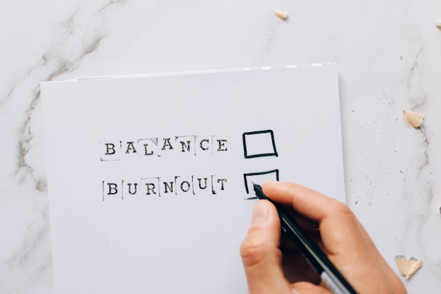 Someone about to tick a box on a checklist that lists “Balance” and “Burnout” on white paper.